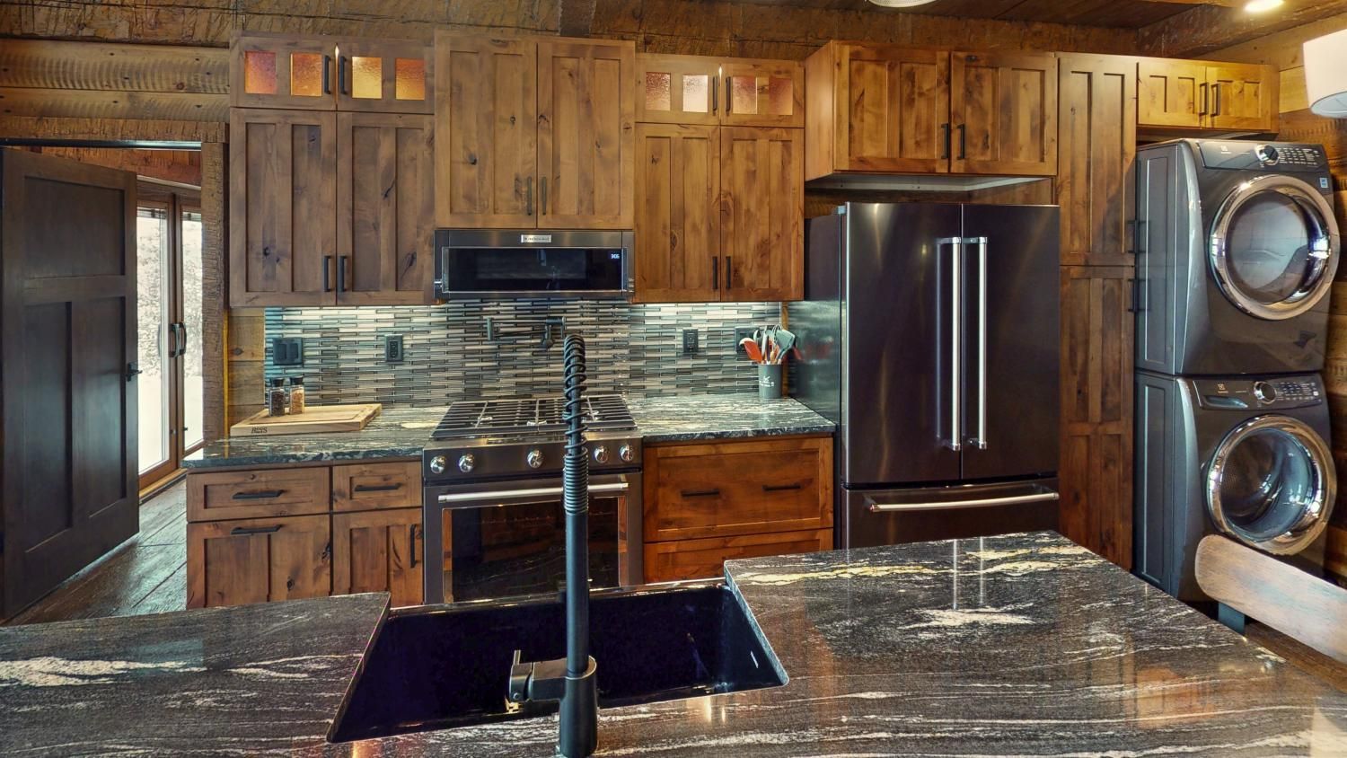 White kitchen with marble countertops, black range, and island.