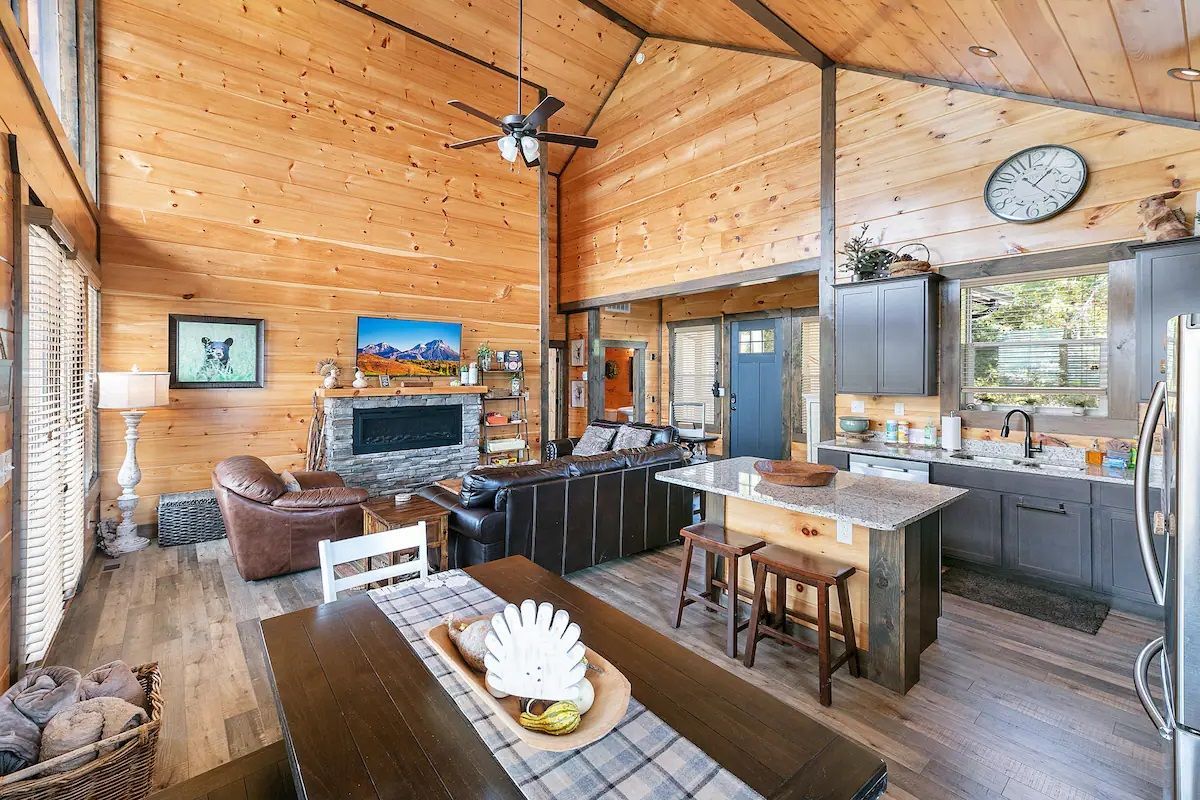 A living room , dining room , and kitchen in a log cabin.