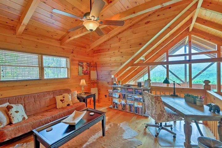 A living room with a couch , coffee table , desk and ceiling fan.