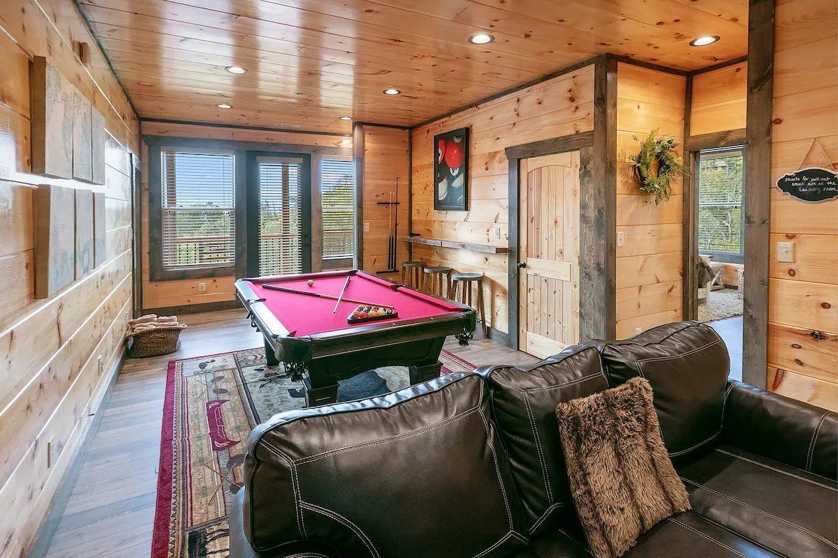 A living room with a pool table and a couch.