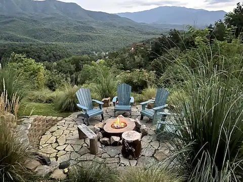 There is a fire pit with chairs around it and a view of the mountains.