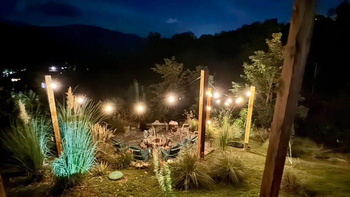 A group of people are sitting around a fire pit at night.