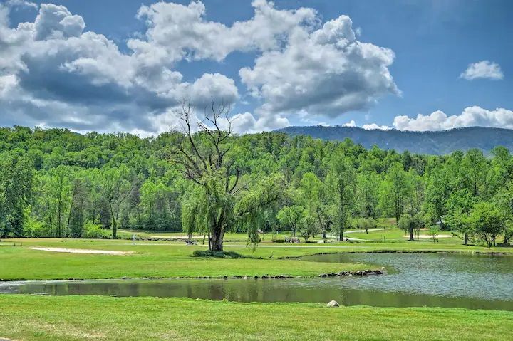There is a lake in the middle of a field with trees in the background.