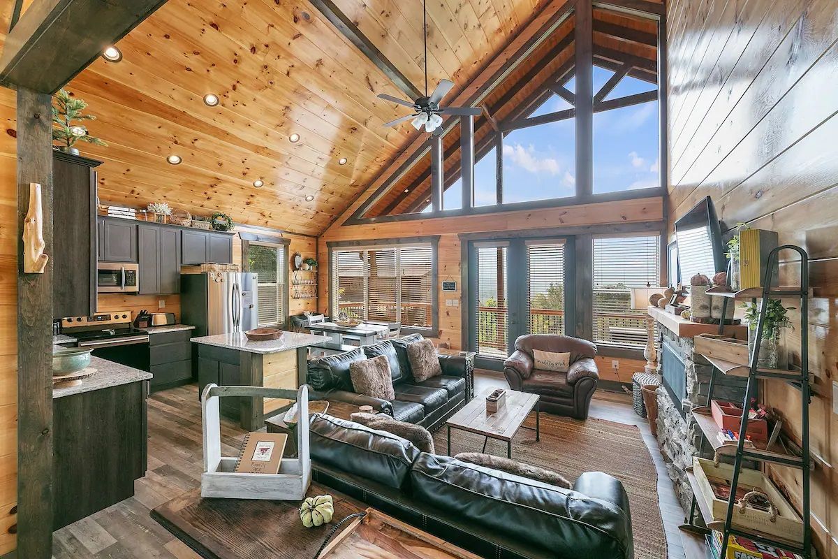 A living room in a log cabin with a vaulted ceiling and lots of windows.