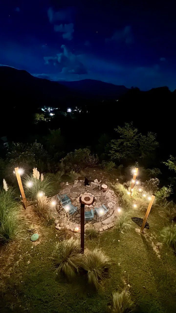 A fire pit is lit up at night in the middle of a field.