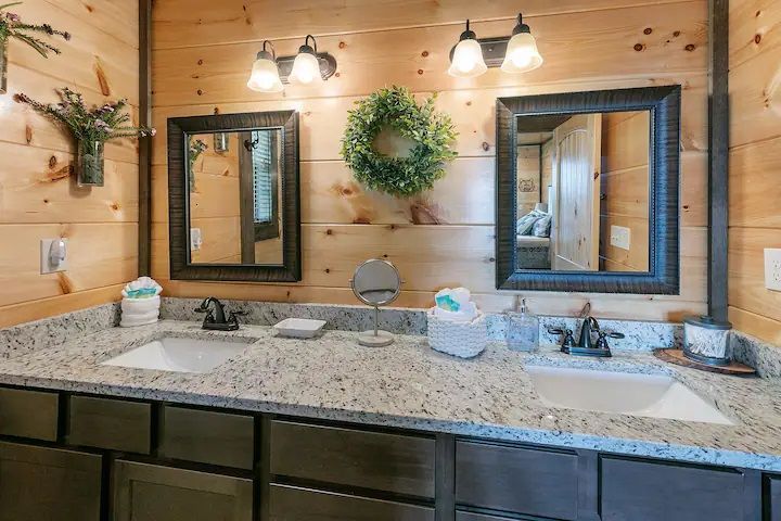 A bathroom in a log cabin with two sinks and two mirrors.