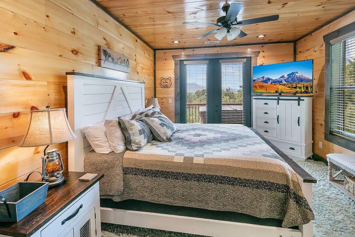 A bedroom in a log cabin with a king size bed and a flat screen tv.