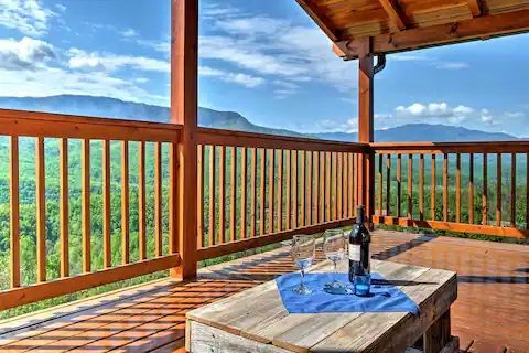 A wooden deck with a bottle of wine and two glasses on it.
