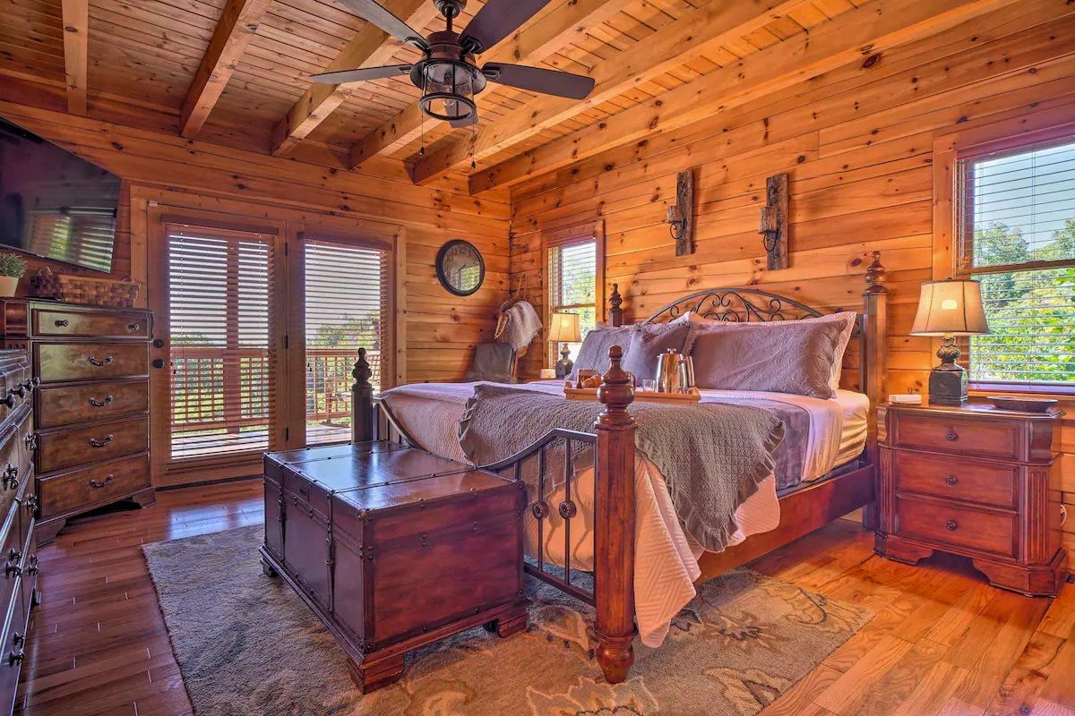 A bedroom in a log cabin with a king size bed and a ceiling fan.