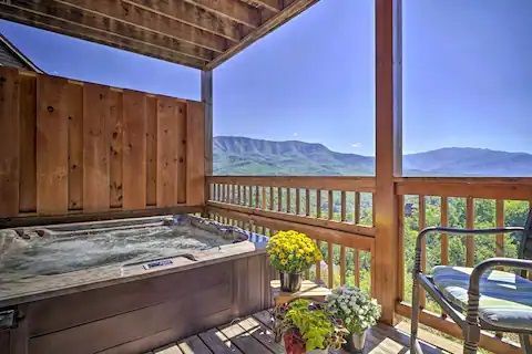 There is a hot tub on the deck with a view of the mountains.