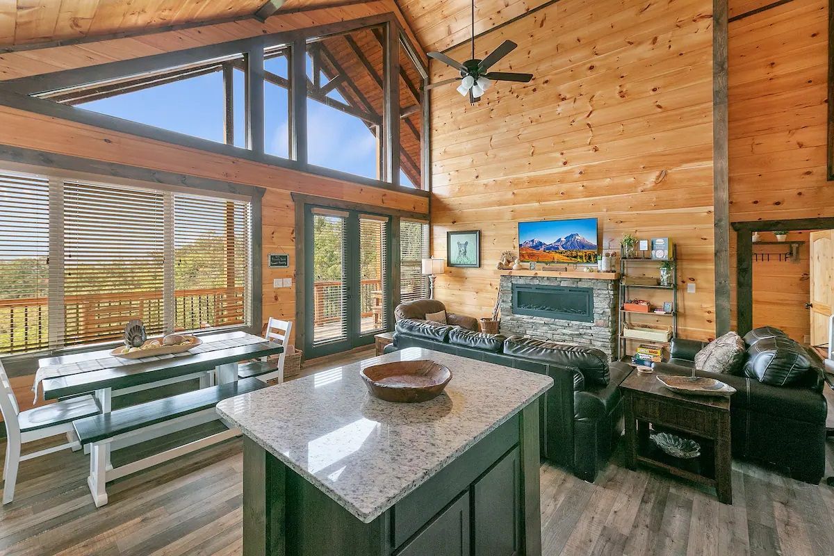 A living room in a log cabin with a large island in the middle.