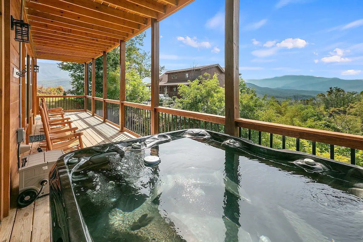 There is a hot tub on the deck of a cabin with a view of the mountains.