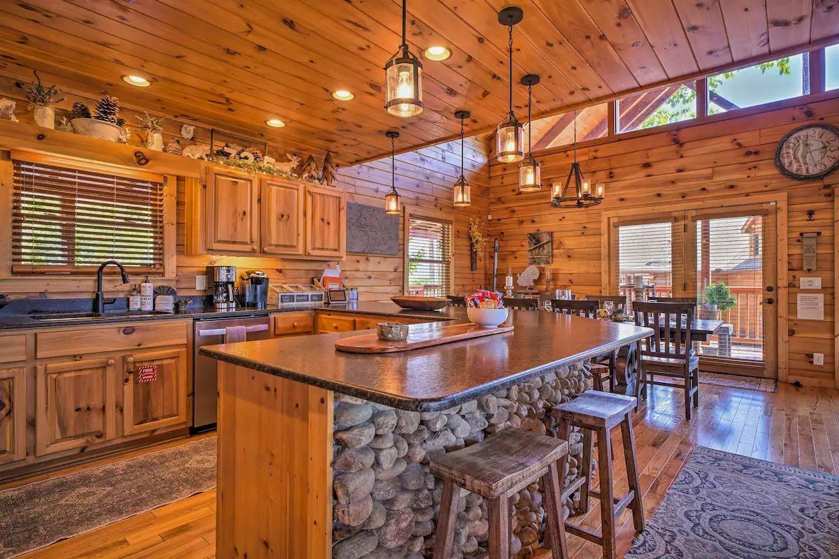 A kitchen in a log cabin with a large island and stools.