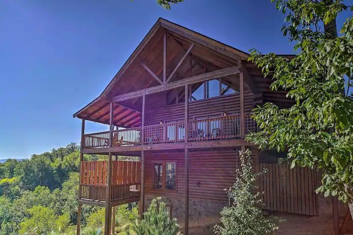 A large log cabin sitting on top of a hill surrounded by trees.