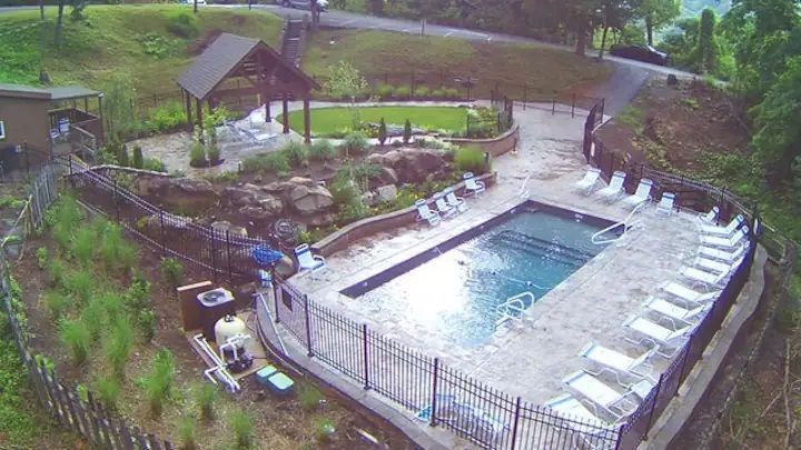An aerial view of a large swimming pool surrounded by chairs and a fence.