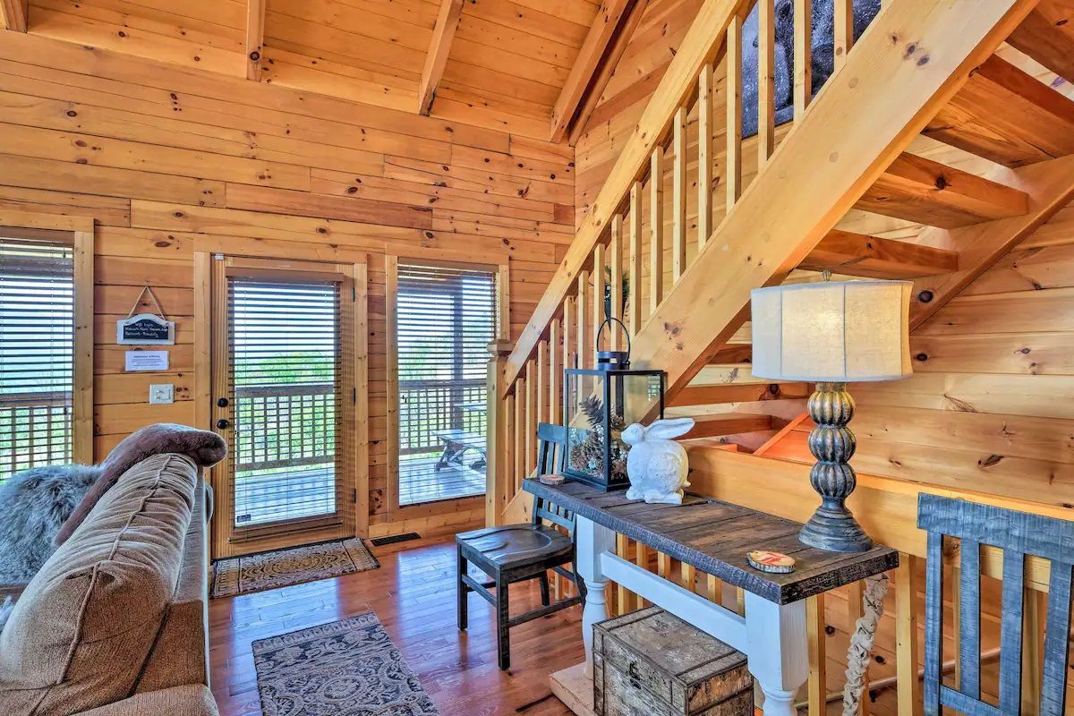 A living room in a log cabin with stairs leading up to the second floor.