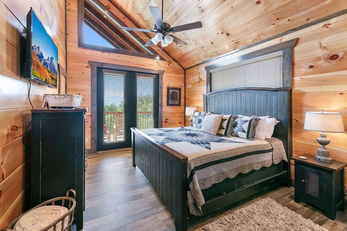 A bedroom in a log cabin with a king size bed and a flat screen tv.