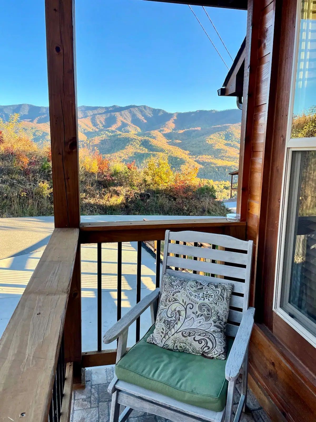 A chair on a porch with a view of mountains.