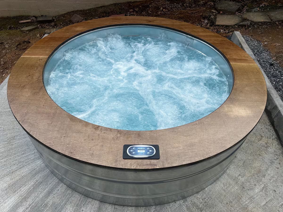 A round hot tub with a wooden top is sitting on the ground.