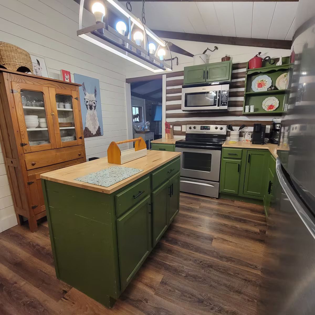 A kitchen with green cabinets and a large island in the middle.