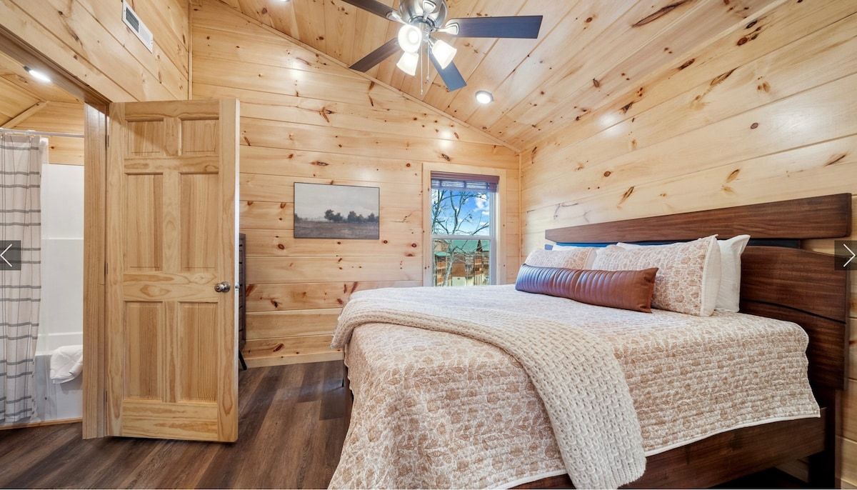 A bedroom in a log cabin with a king size bed and a ceiling fan.