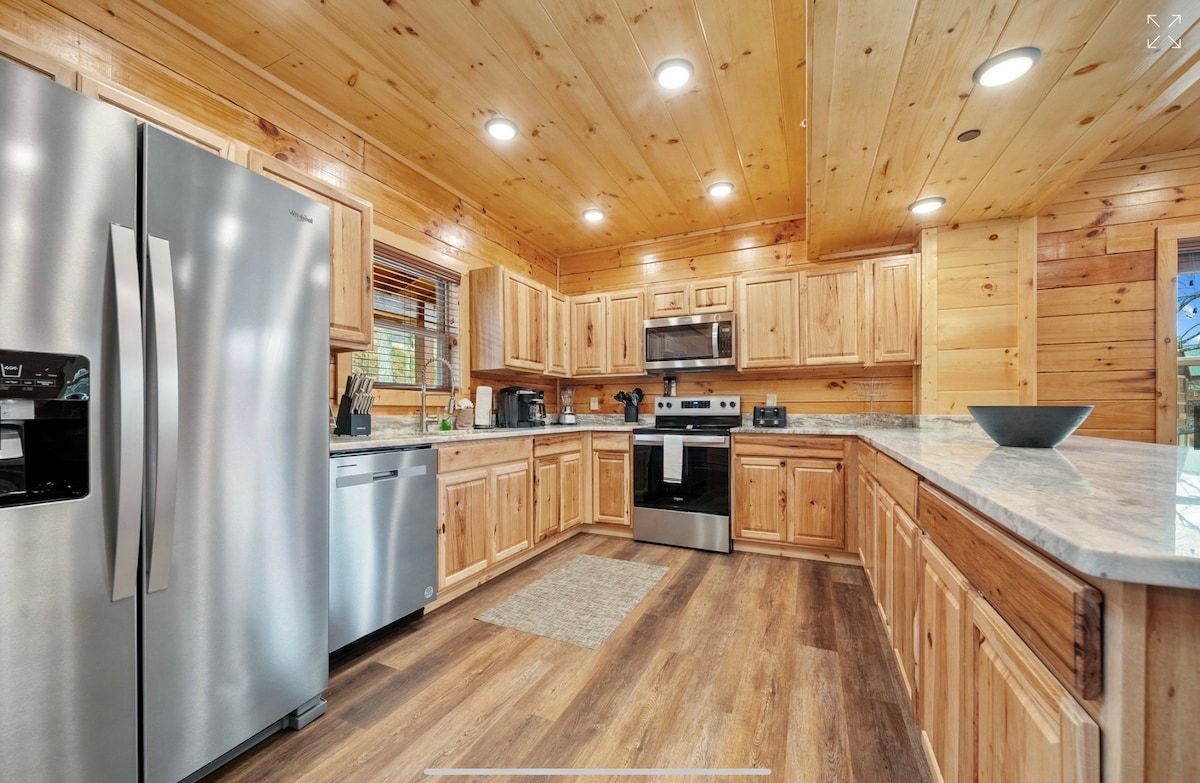 A kitchen in a log cabin with stainless steel appliances and wooden cabinets.