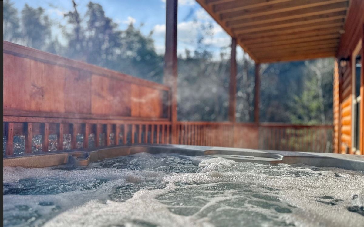 A hot tub is sitting on the deck of a log cabin.