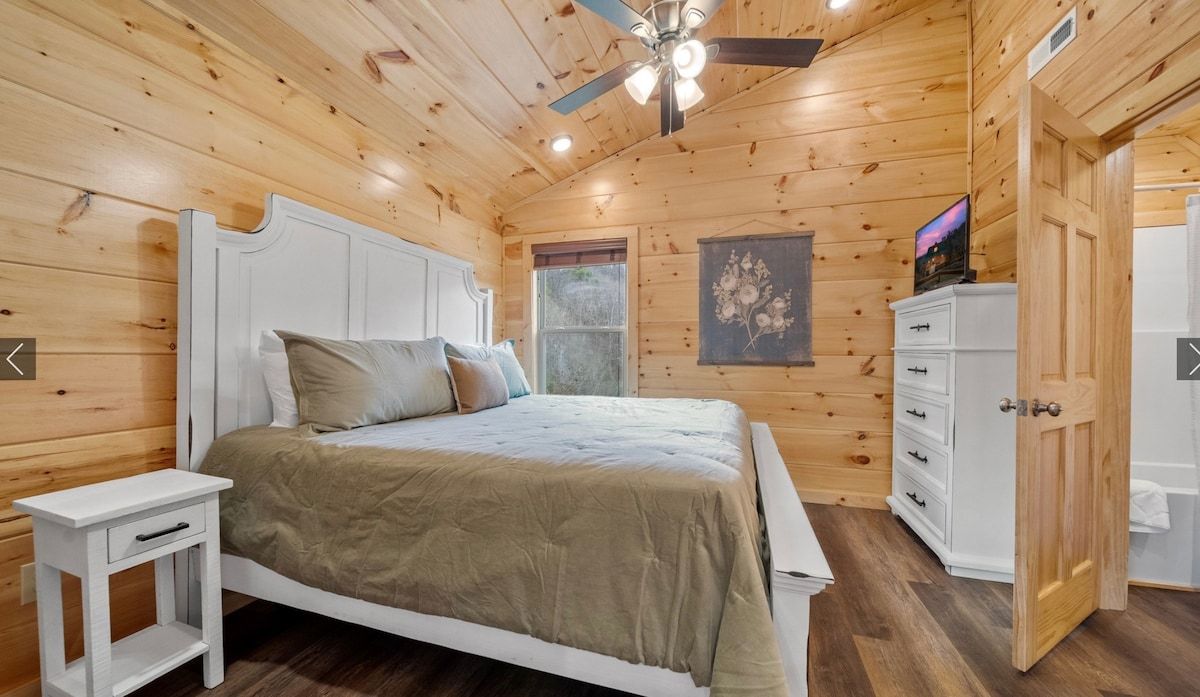 A bedroom in a log cabin with a king size bed and a ceiling fan.