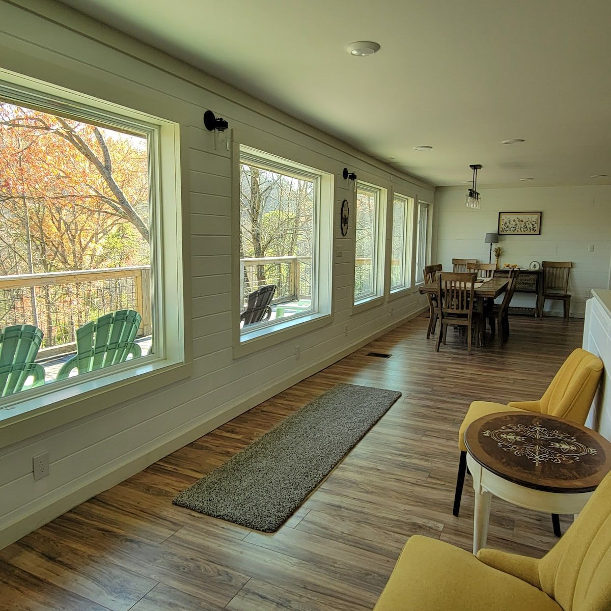 A living room with a lot of windows and a yellow chair
