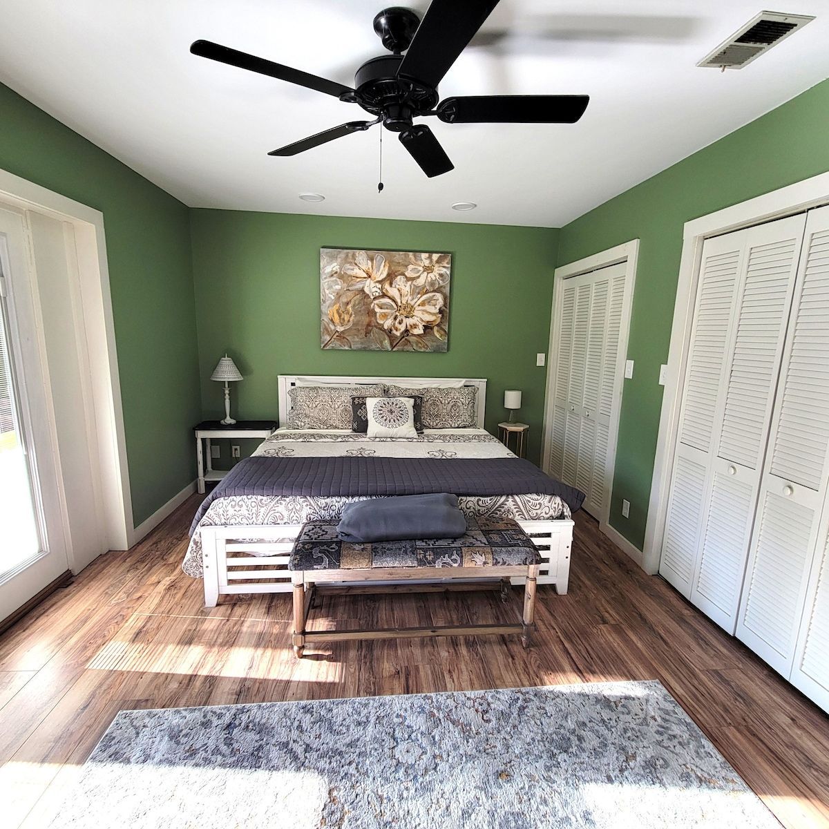 A bedroom with green walls and a ceiling fan