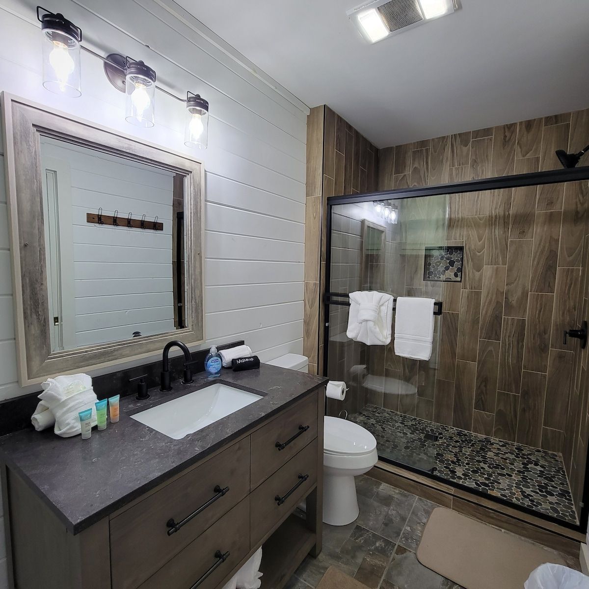 A bathroom with a toilet , sink , mirror and shower.