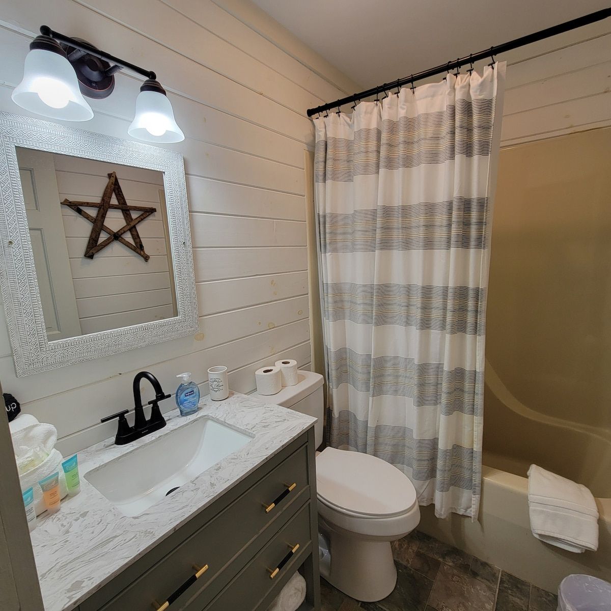 A bathroom with a toilet , sink , mirror and shower curtain