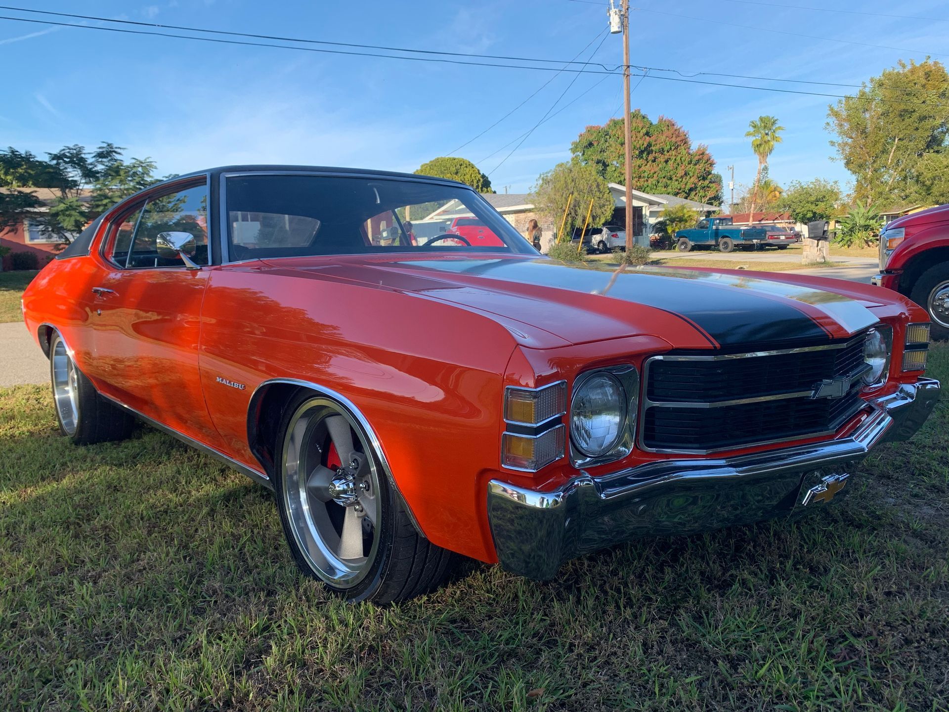 A red chevrolet chevelle is parked in a grassy field.
