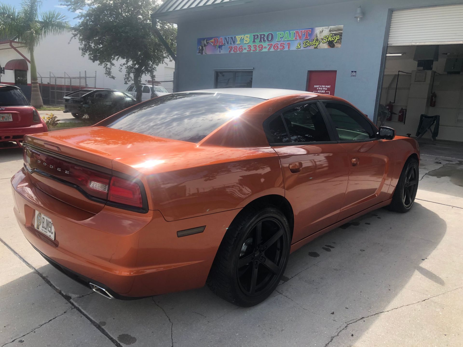 An orange dodge charger is parked in front of a building.