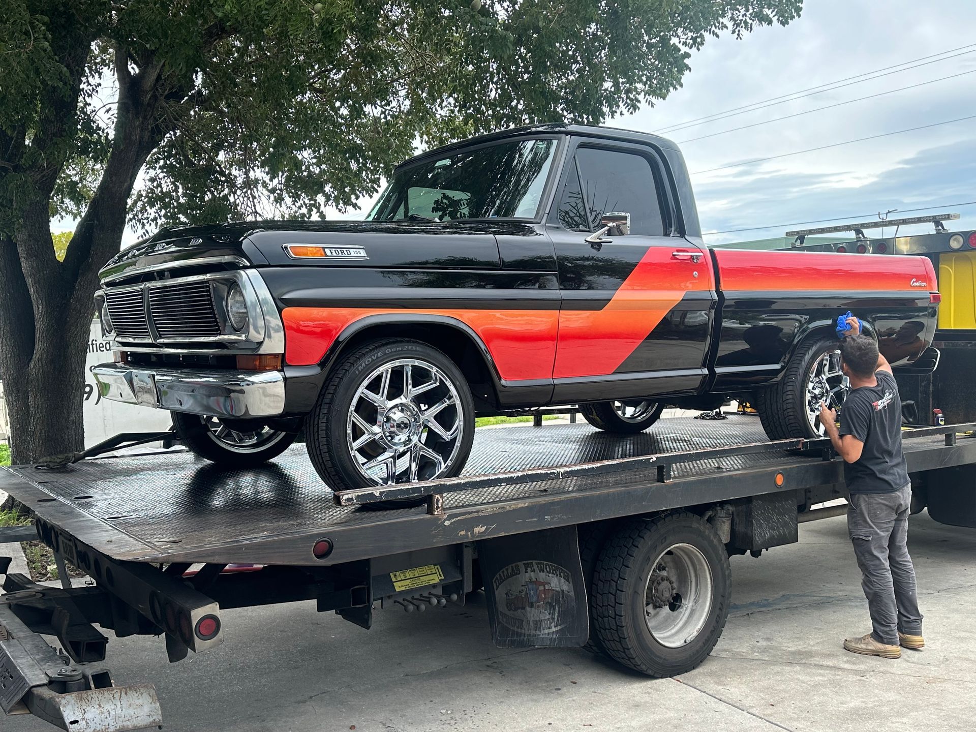 A black and red truck is sitting on top of a tow truck.