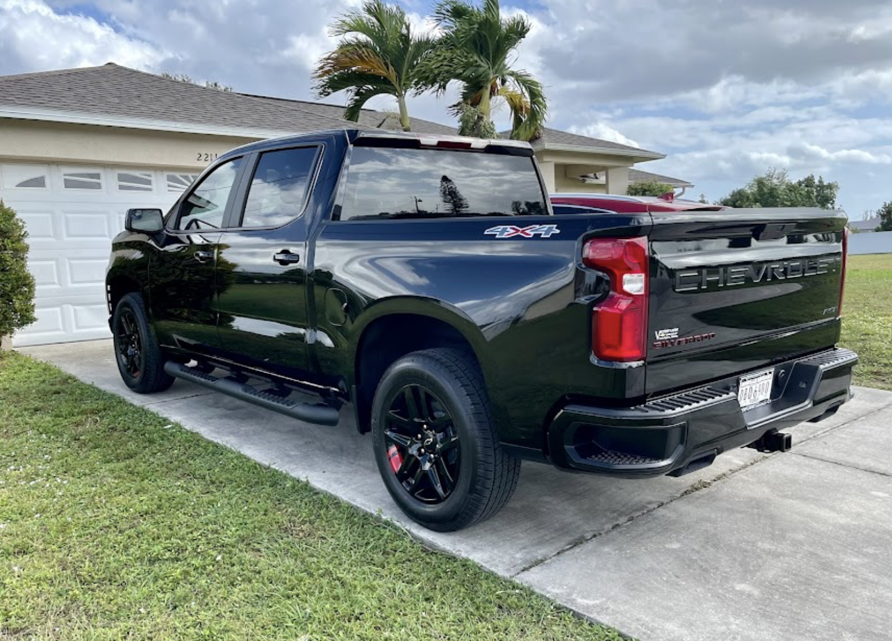 A black truck is parked in front of a house.