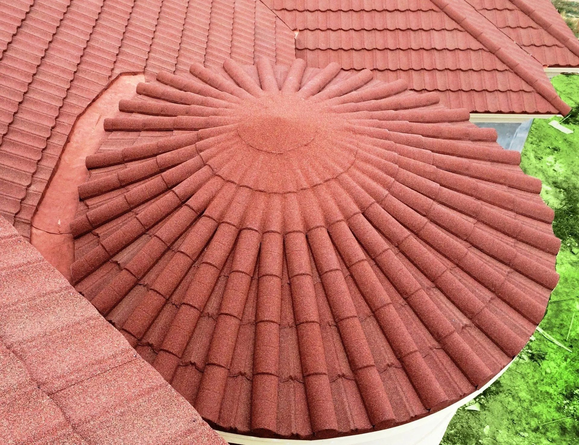 A high-angle view of a red, circular, tile-covered roof section seamlessly integrated into a larger sloped roof.