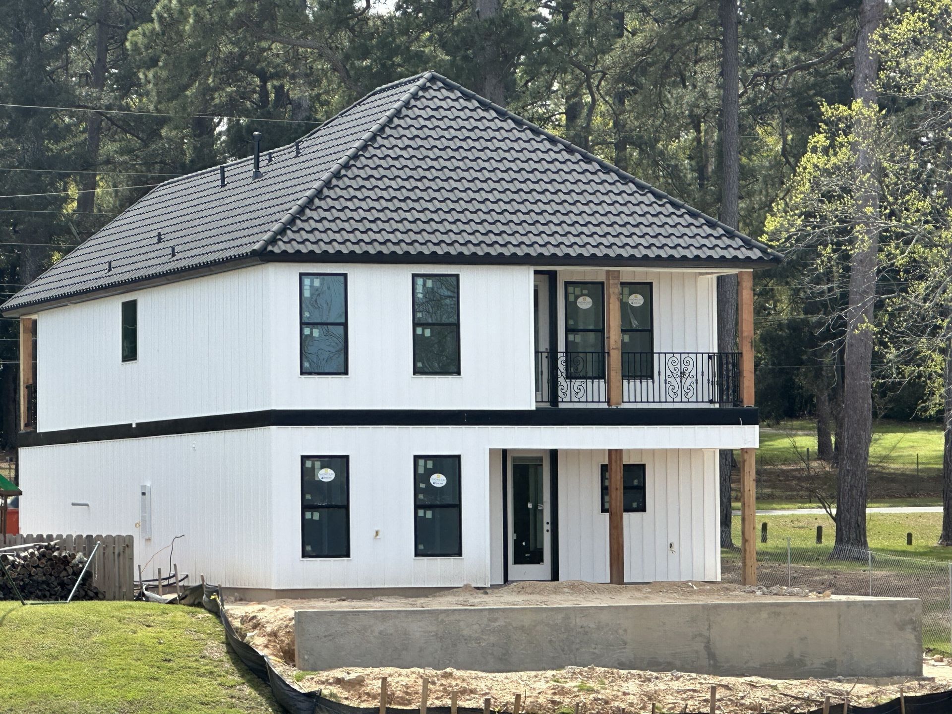 Two-story modern home with white vertical siding, black-framed windows, a dark hip roof, and a covered front porch.
