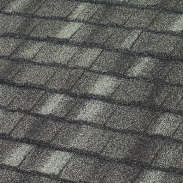 A close-up view of charcoal gray architectural roofing shingles with a textured, layered pattern.