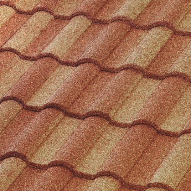 A close-up of overlapping roof tiles in alternating shades of reddish-brown and tan with a textured, granular finish.