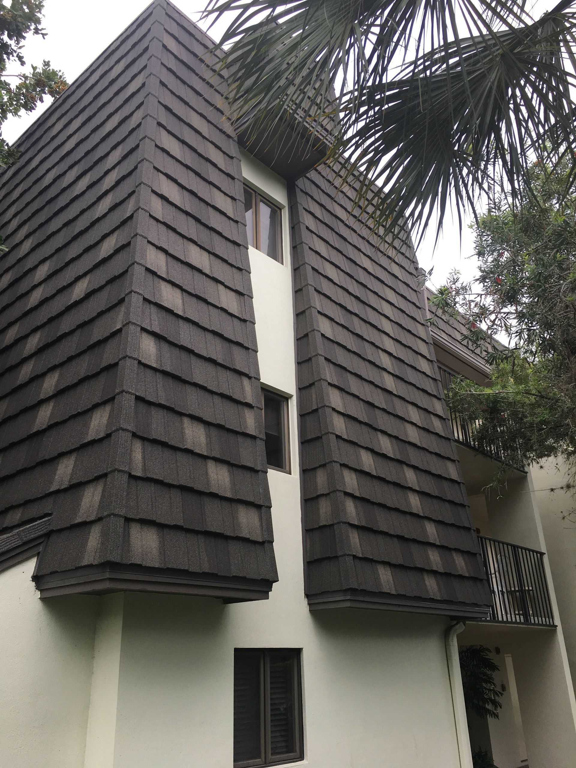 A multi-story building featuring distinctive, dark-shingled vertical exterior panels against a light-colored wall.