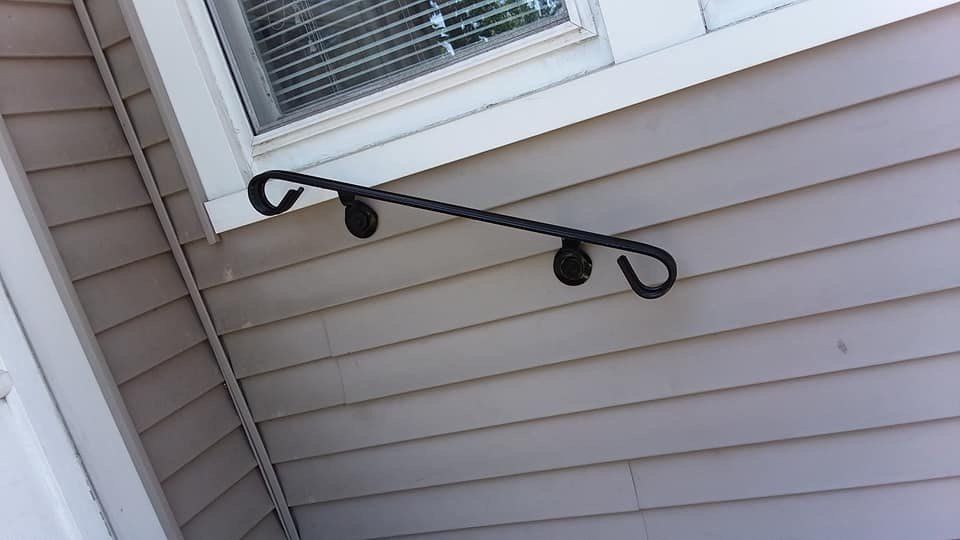 A black railing is attached to the side of a house next to a window