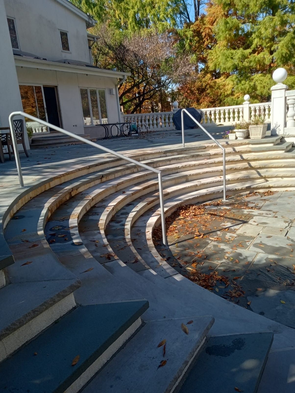 A set of curved stairs with a railing in front of a house