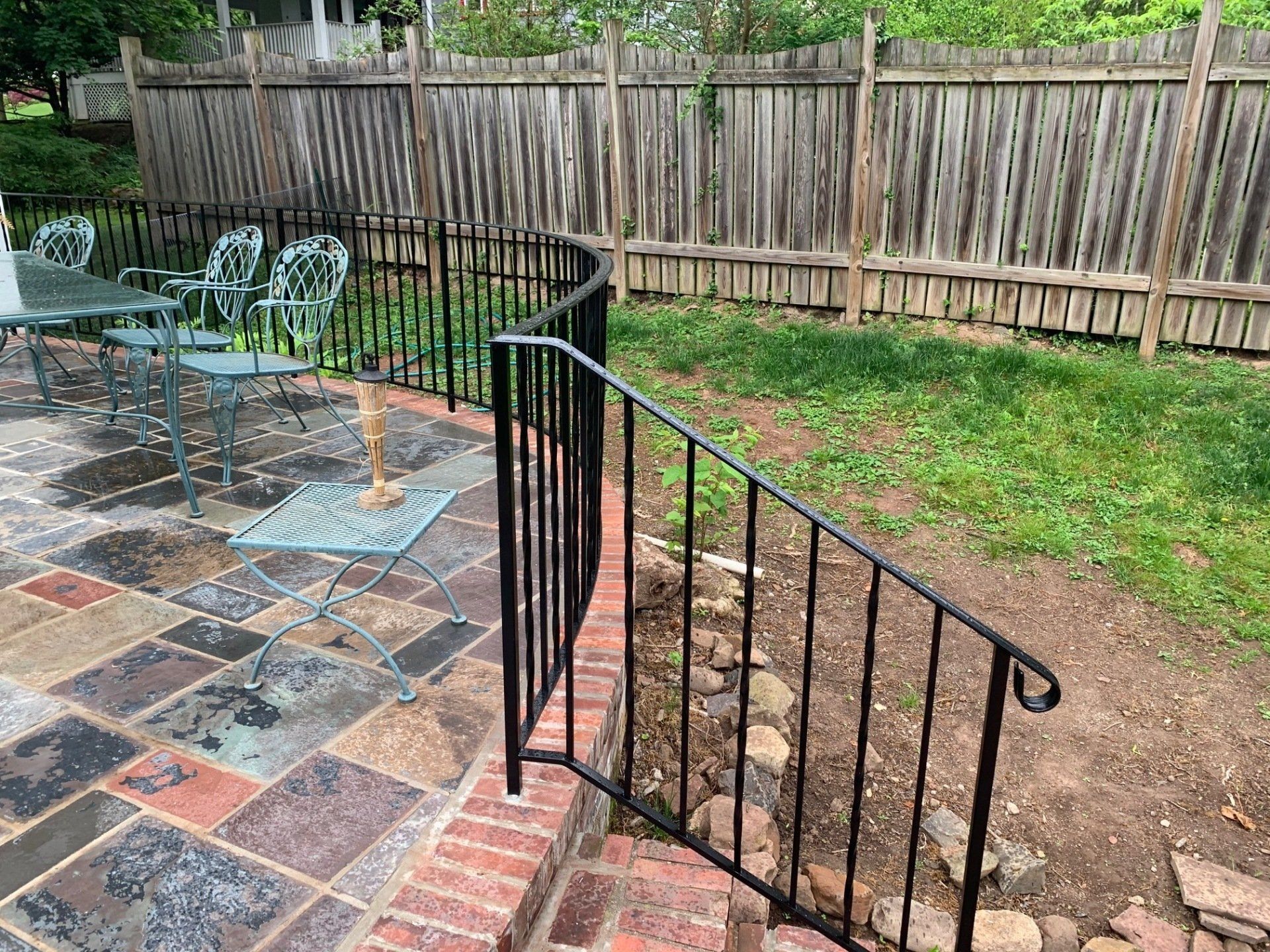 A patio with a table and chairs and a wrought iron railing