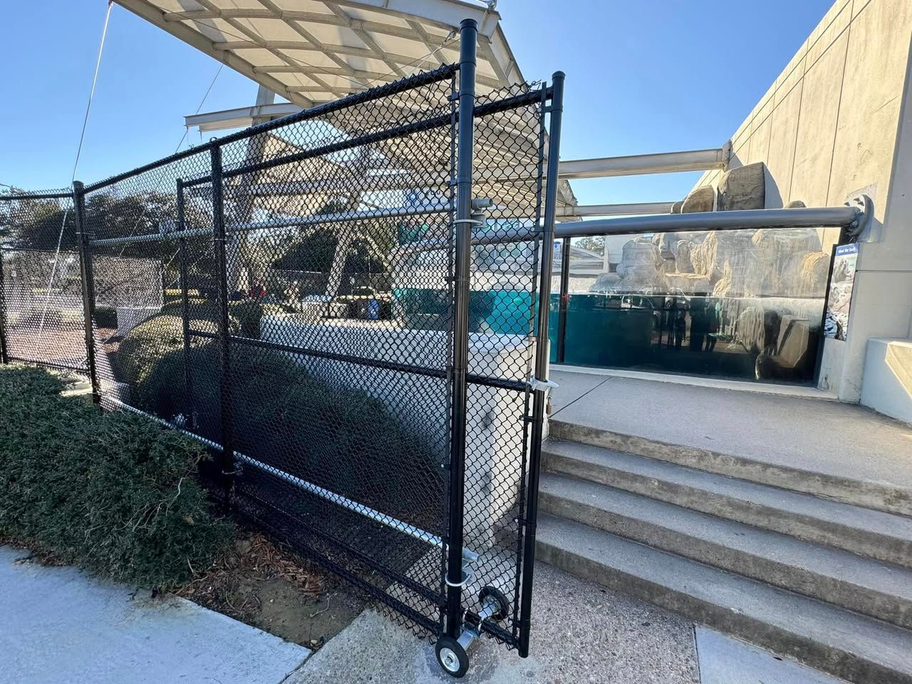A chain link fence is surrounding a pool and stairs.