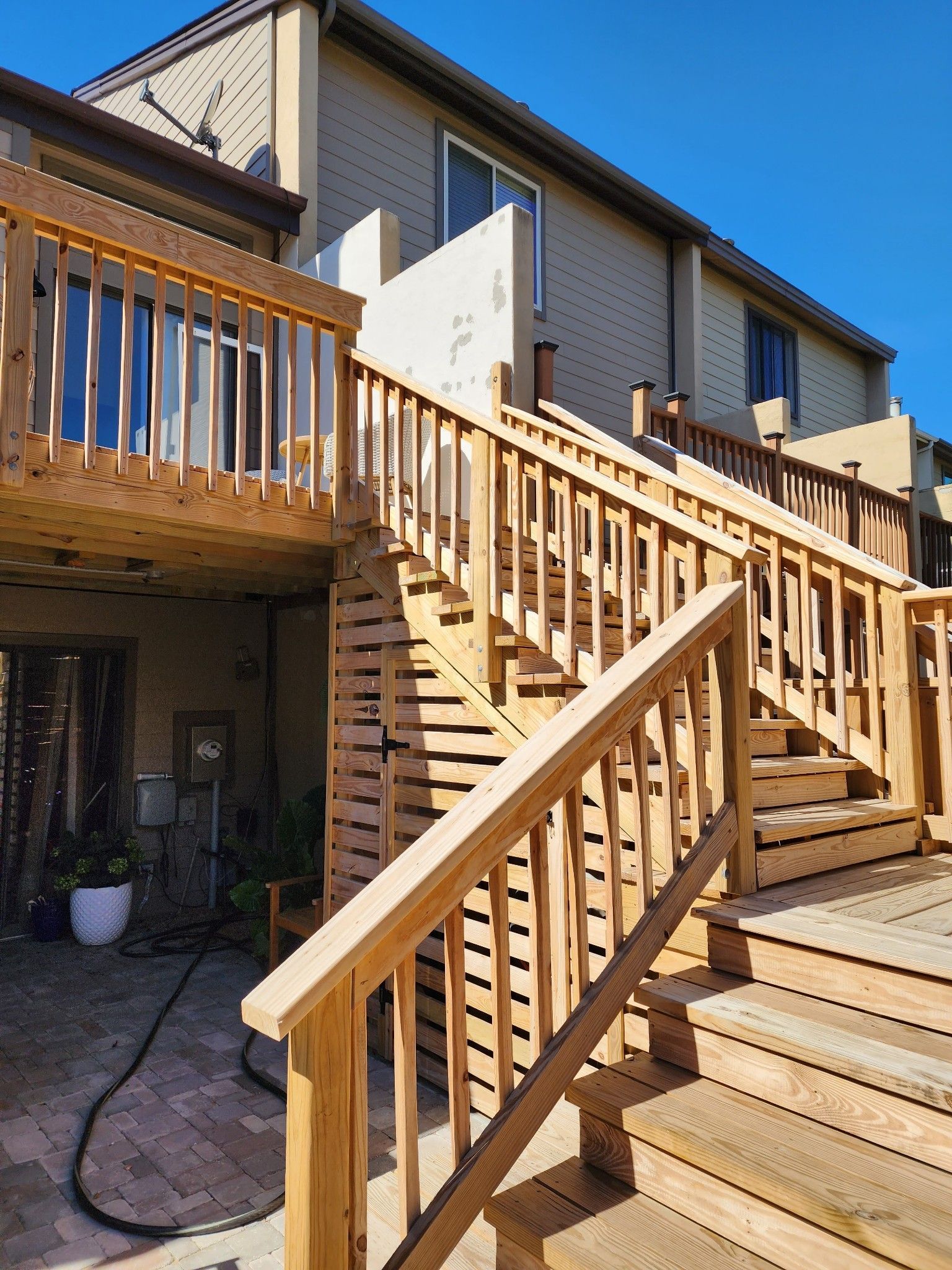 A wooden deck with stairs leading up to it and a house in the background.