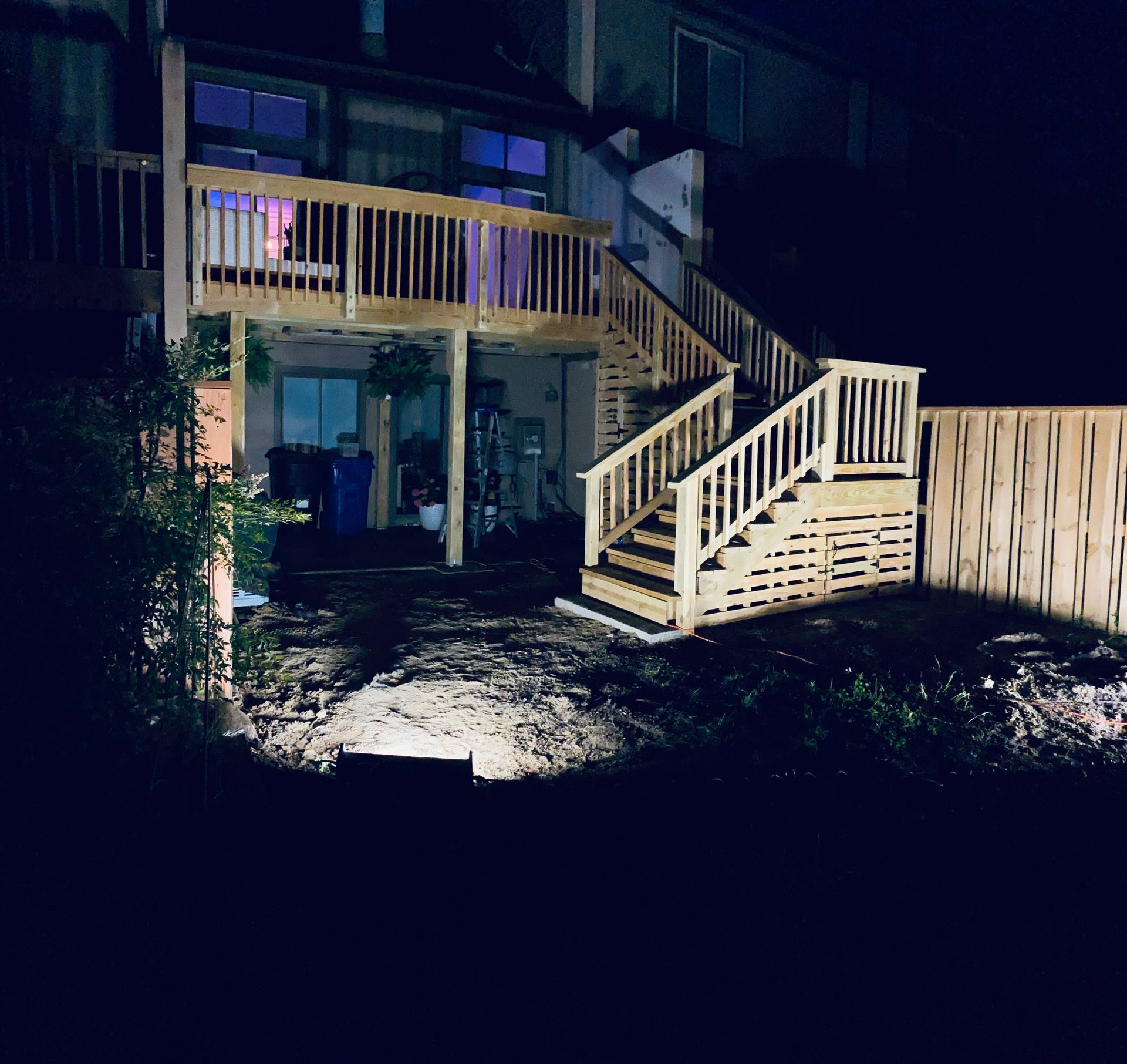A house with a wooden deck and stairs at night