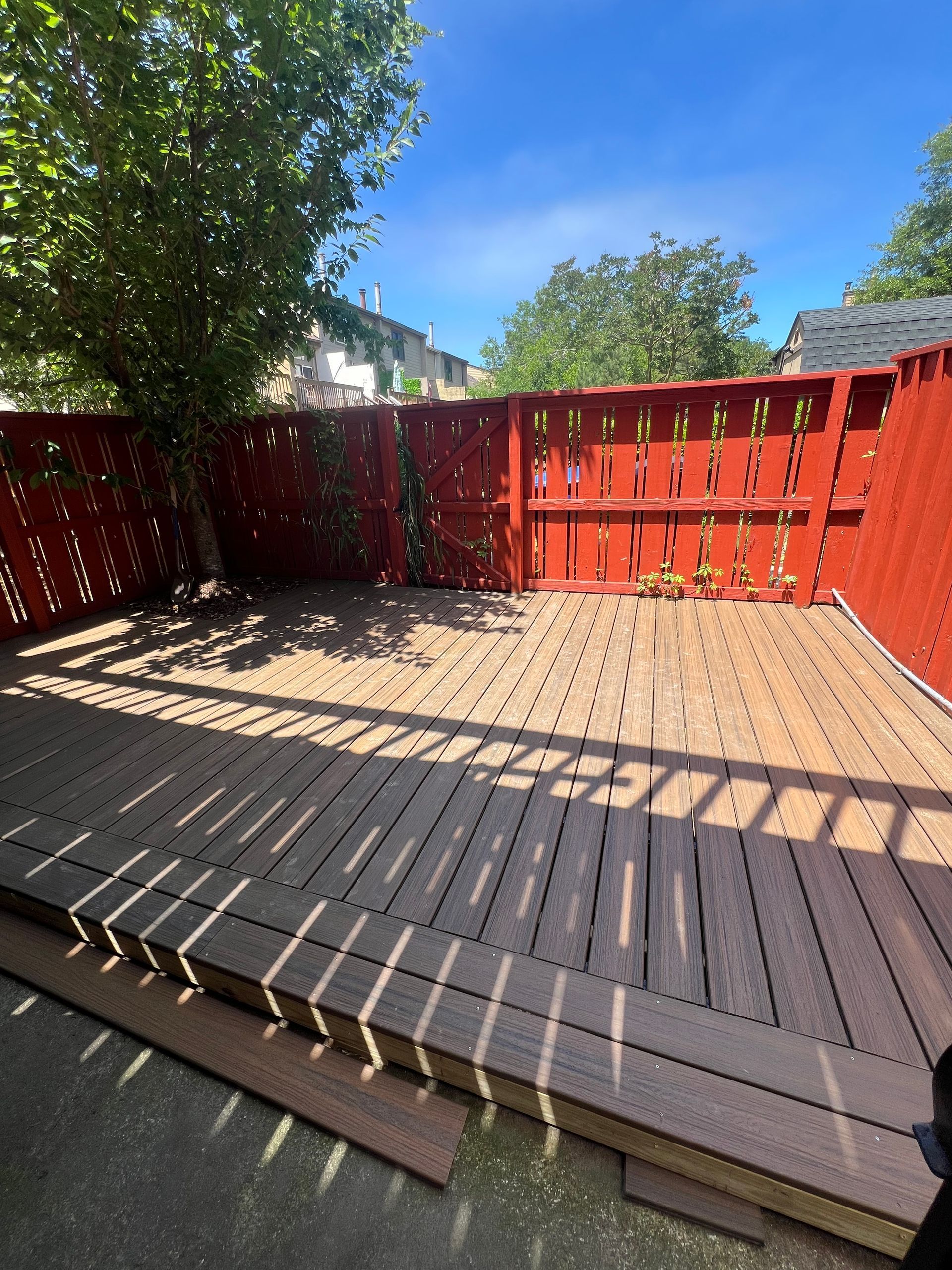 A wooden deck with a red fence in the background