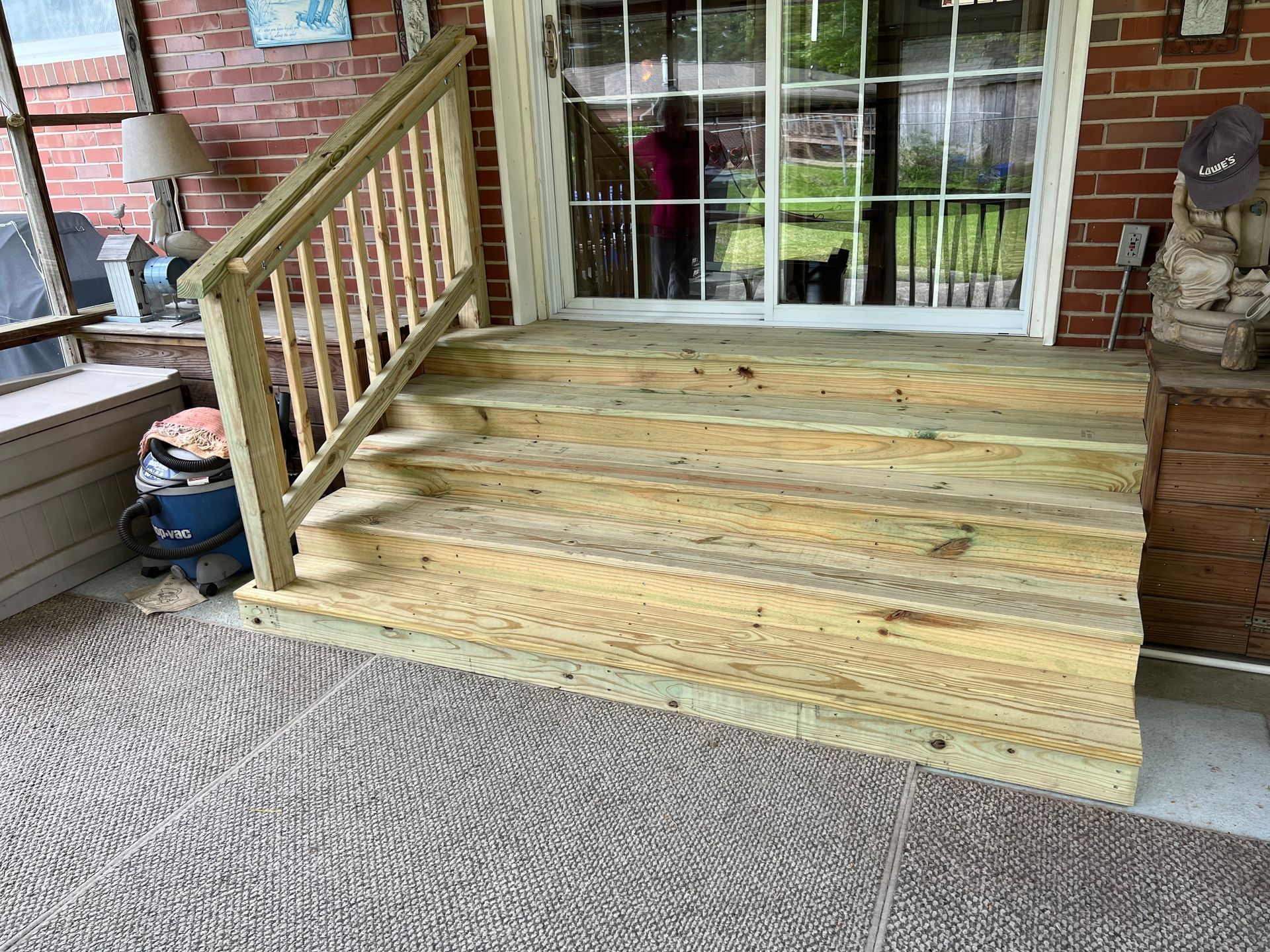 A wooden deck with stairs and a railing on a brick house.