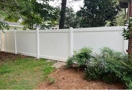 A white vinyl fence is in the backyard of a house.